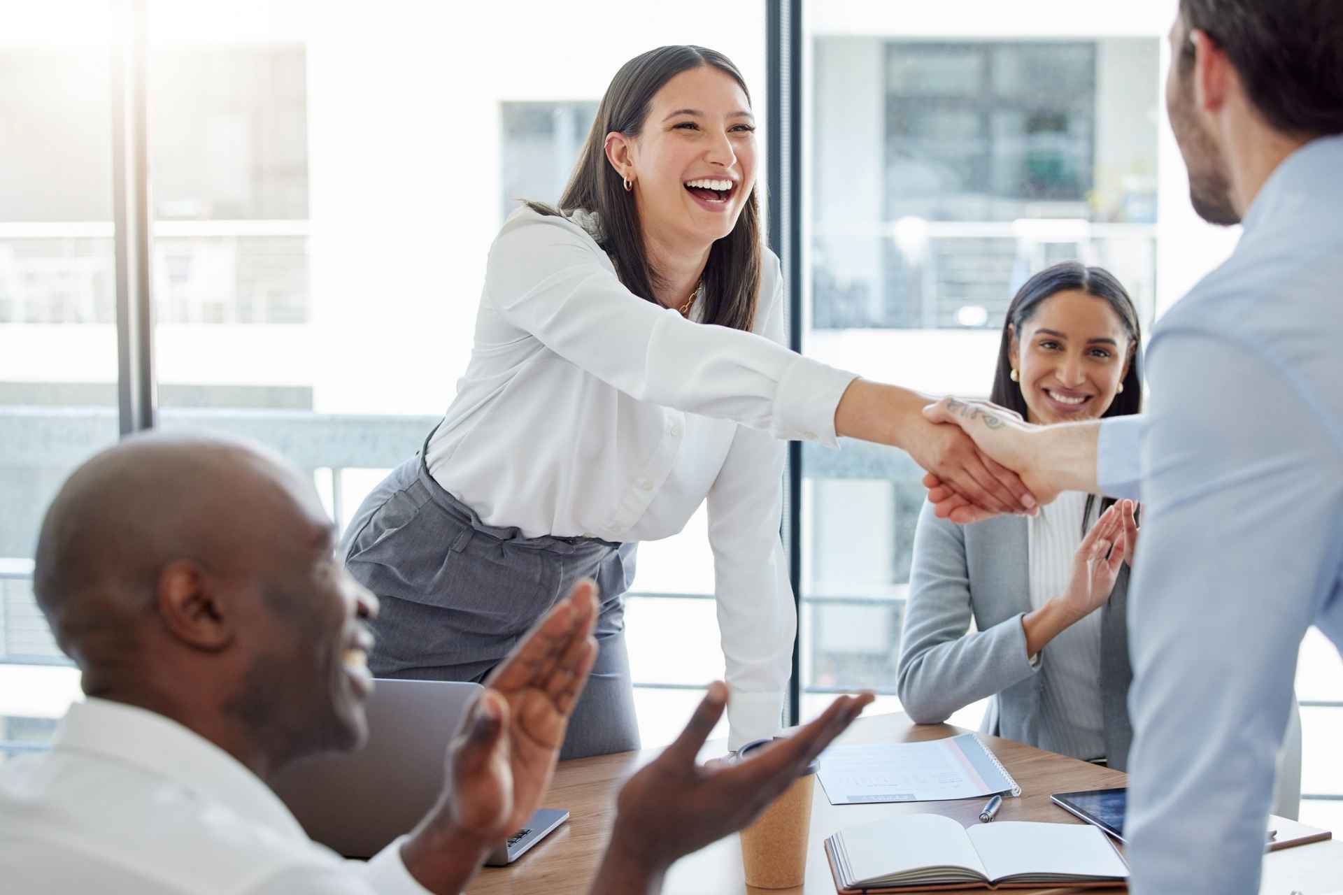 Woman in a white shit shaking someones hand